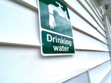 Image shows a tap with sign above that reads 'drinking water.'