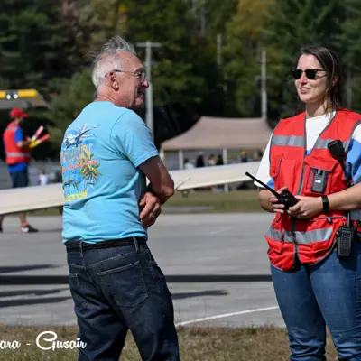 Image shows a volunteer talking to a fly-in attendee. 