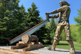 Image shows a sculpture of a lumberjack sawing a log. 