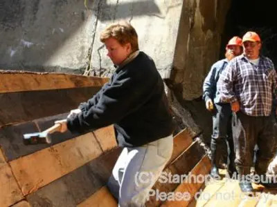 Image shows men working on the largely completed log chute. 