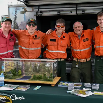 Image shows a group of MNRF firefighters at an information booth. 