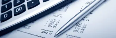 Image shows a calculator, pen and financial documents. 