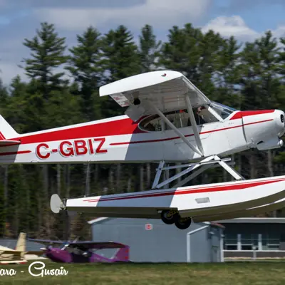 Image shows a red and white pontoon plane taking off. 