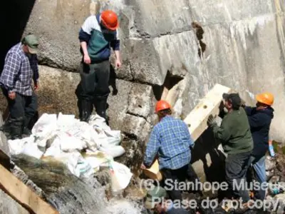 Image shows a group of people working at the foot of the dam. 