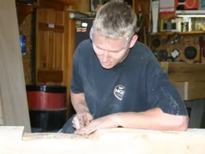 Image shows a man doing wood-working. 