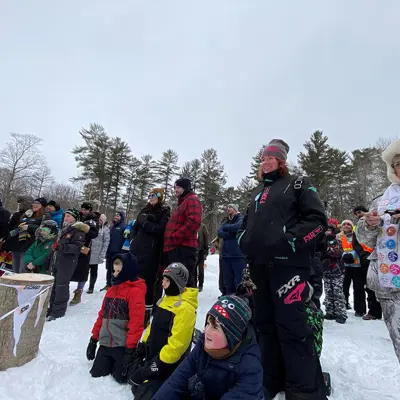 Image shows a crowd of onlookers watching a lumberjack show. 