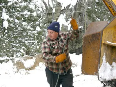 Image shows a man in toque operating a machine. 