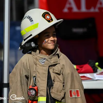 Image shows a child wearing firefighting equipment.
