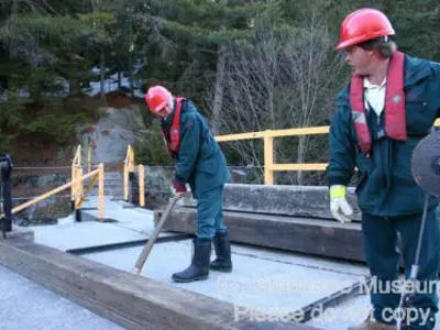 Image shows people working on top of the dam. 