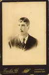 Image shows a portrait of a young man with a moustache. 