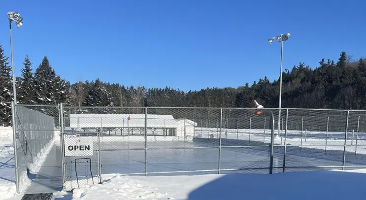 Image shows outdoor skating rink surrounded by a fence. 