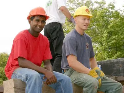 Image shows two men in hardhats taking a break. 