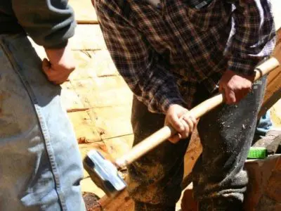 Image shows a man working with a sledgehammer. 