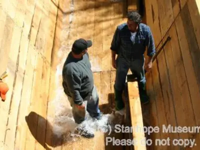 Image shows members of the construction team walking on the largely completed log chute. 