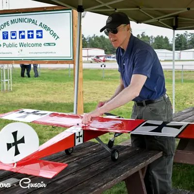 Image shows a man with a model airplane. 