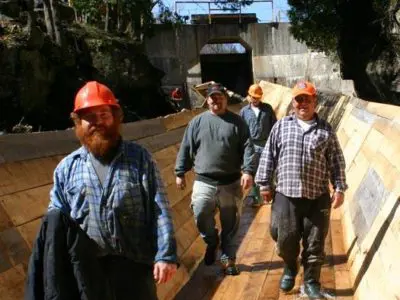 Image shows members of the construction team posing on the completed log chute. 