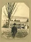 Image shows a picture of a child standing outdoors with a tree and a rock wall in the background. 