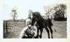 Image shows a black and white photo of a man with a horse standing behind him. 