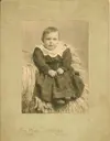 Image shows a black and white photo of a baby in a gown. 